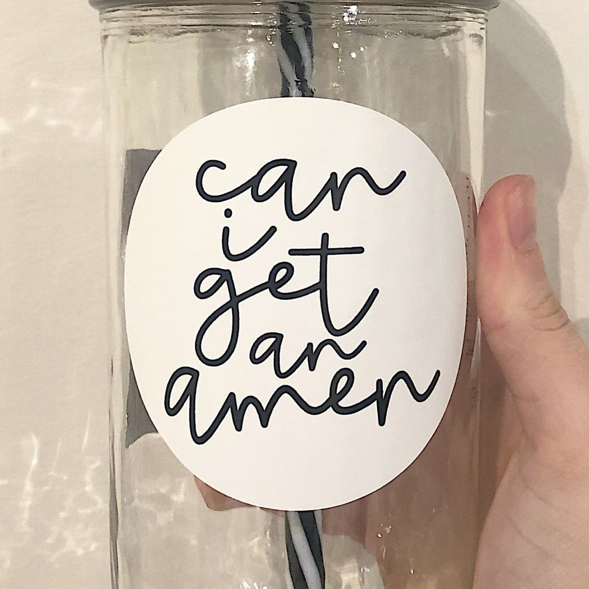 Close up of a hand holding a mason jar tumbler that says "can I get an amen”