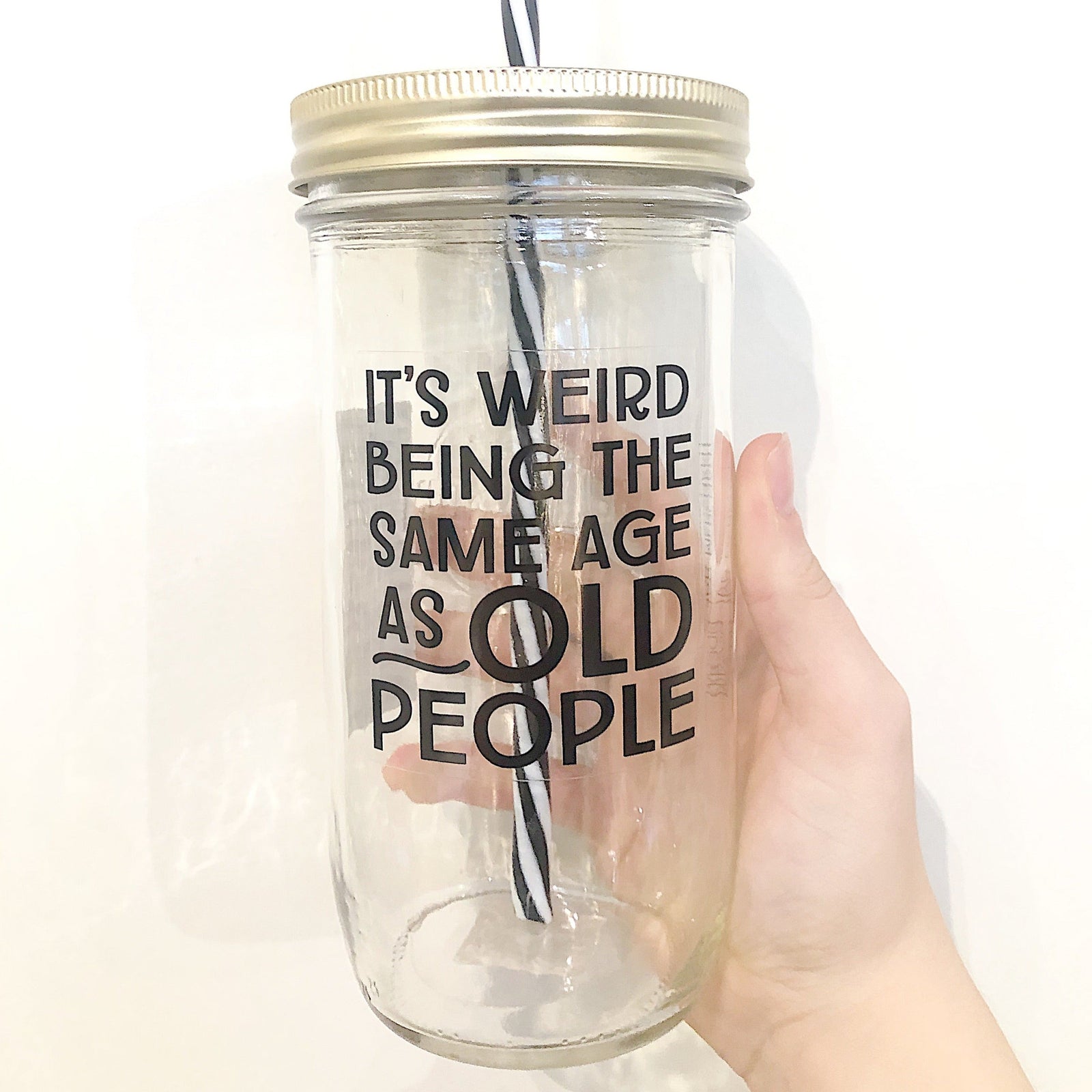Hand holding a mason jar tumbler that says “It’s weird being the same age as old people”