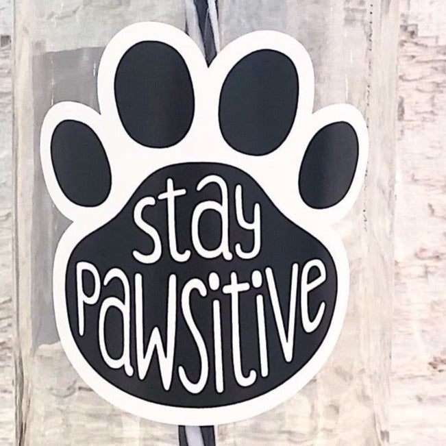 Close up of a mason jar tumbler that has a black paw print and in the paw print says “stay pawsitive”