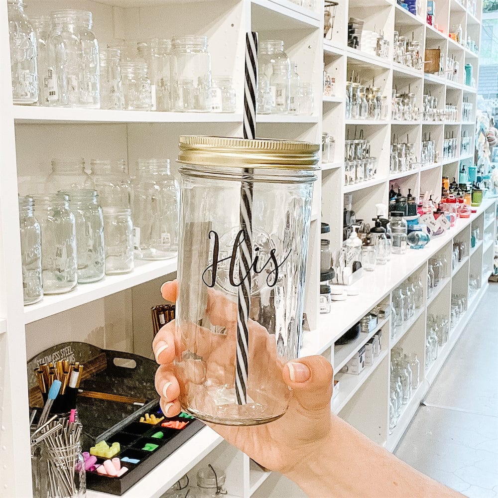 A photo of a mason jar tumbler with a sticker text that says "His"