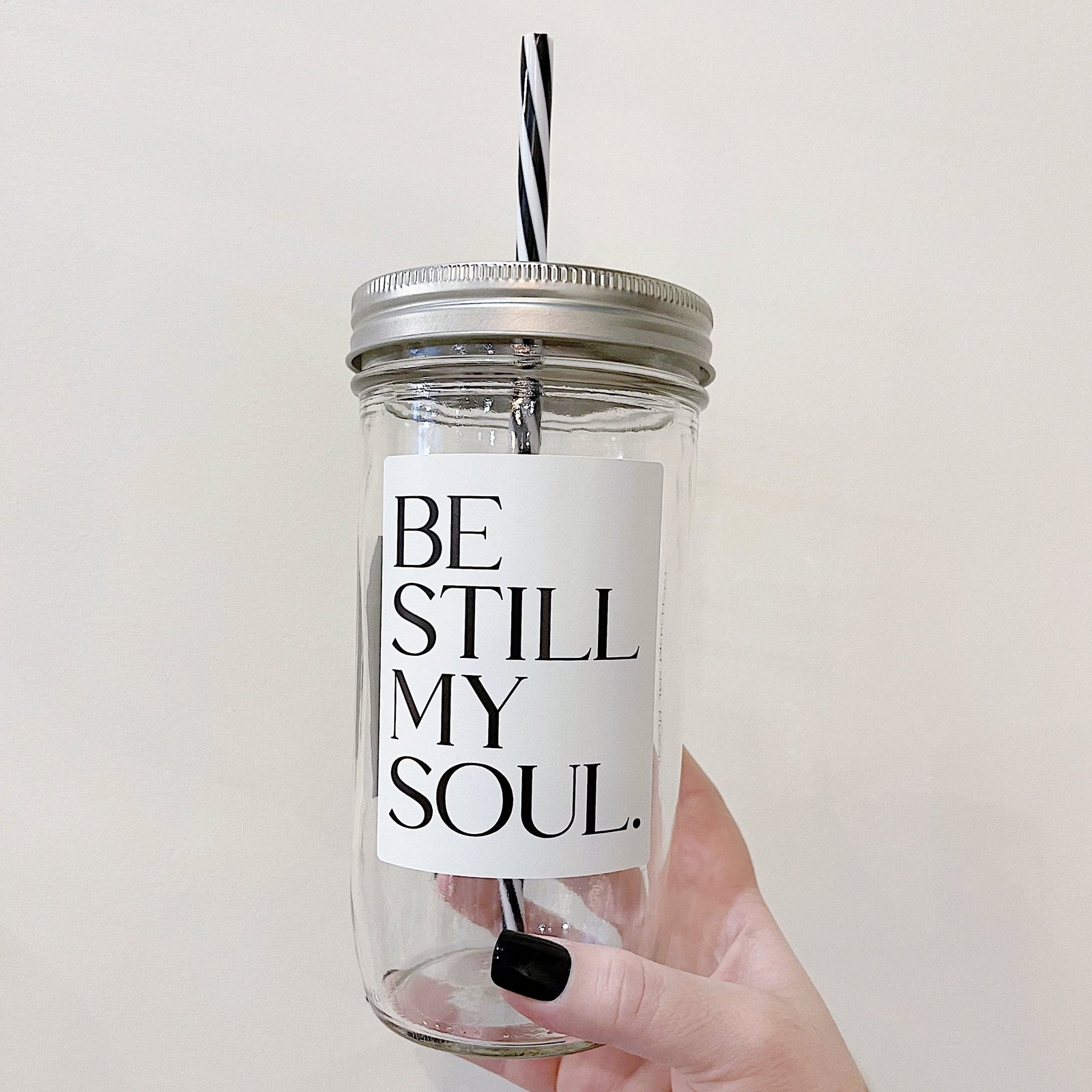 Hand holding a mason jar tumbler that says "be still my soul”