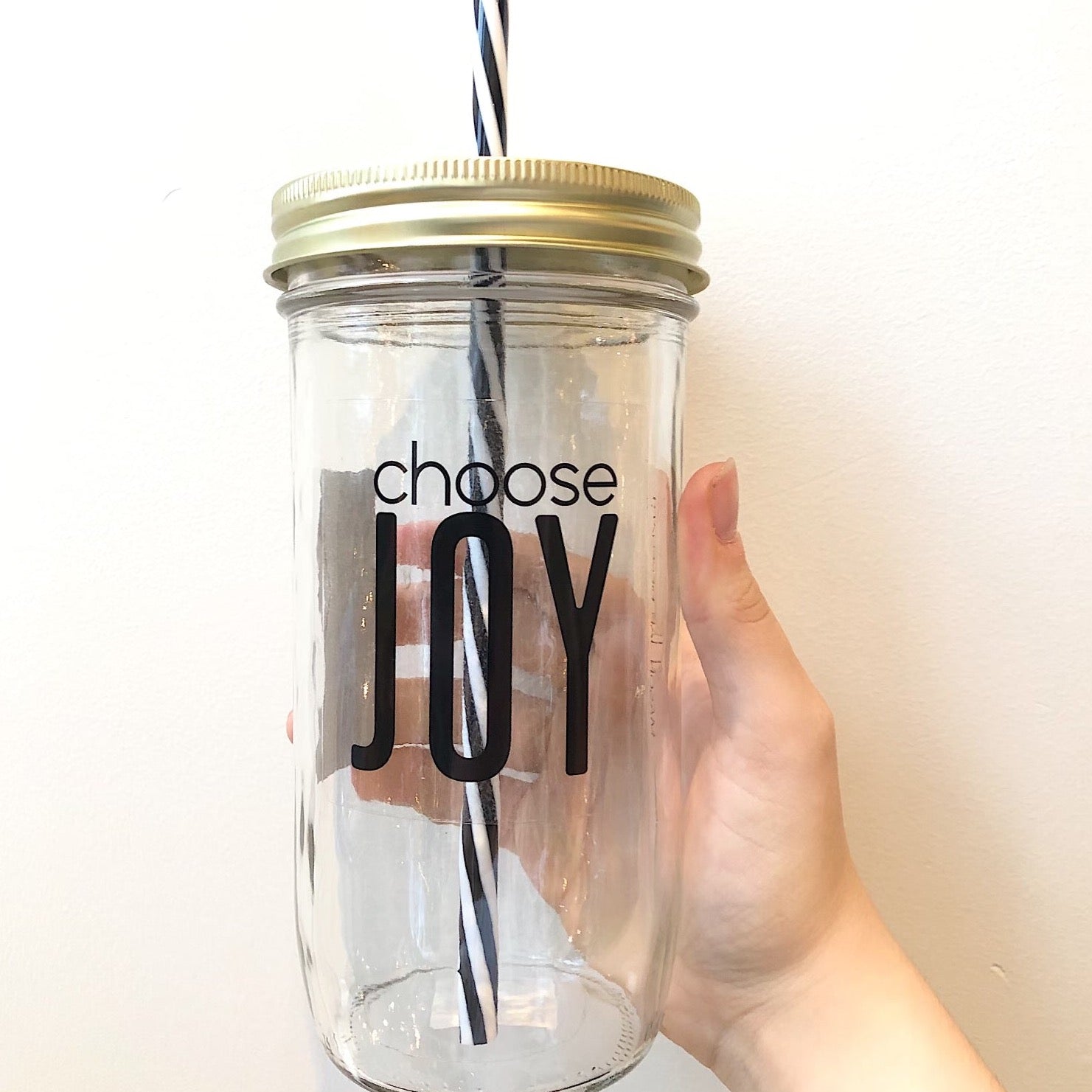 Hand holding a mason jar tumbler that says “choose joy”