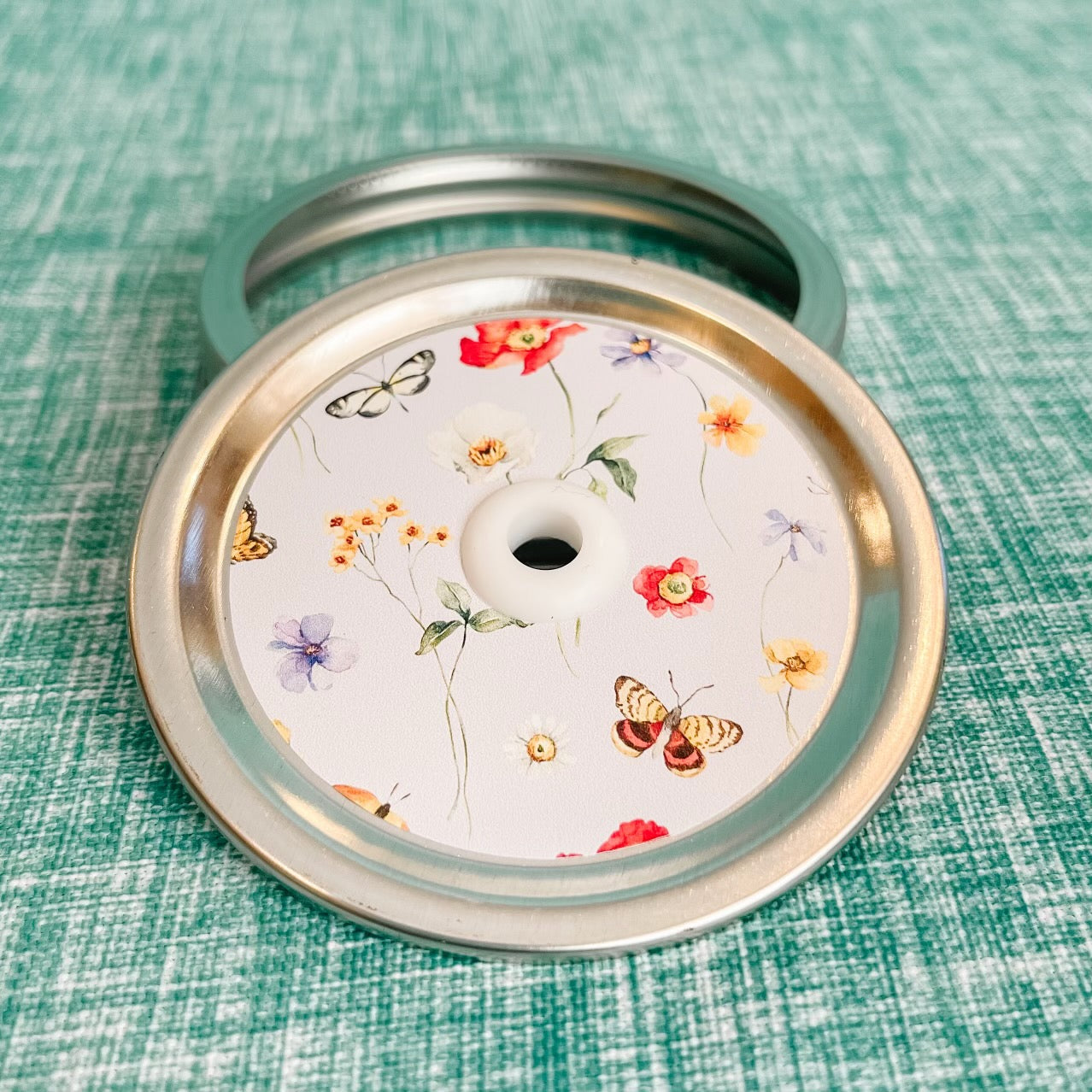 straw lid with pale blue background, single flowers, butterflies are scattered across