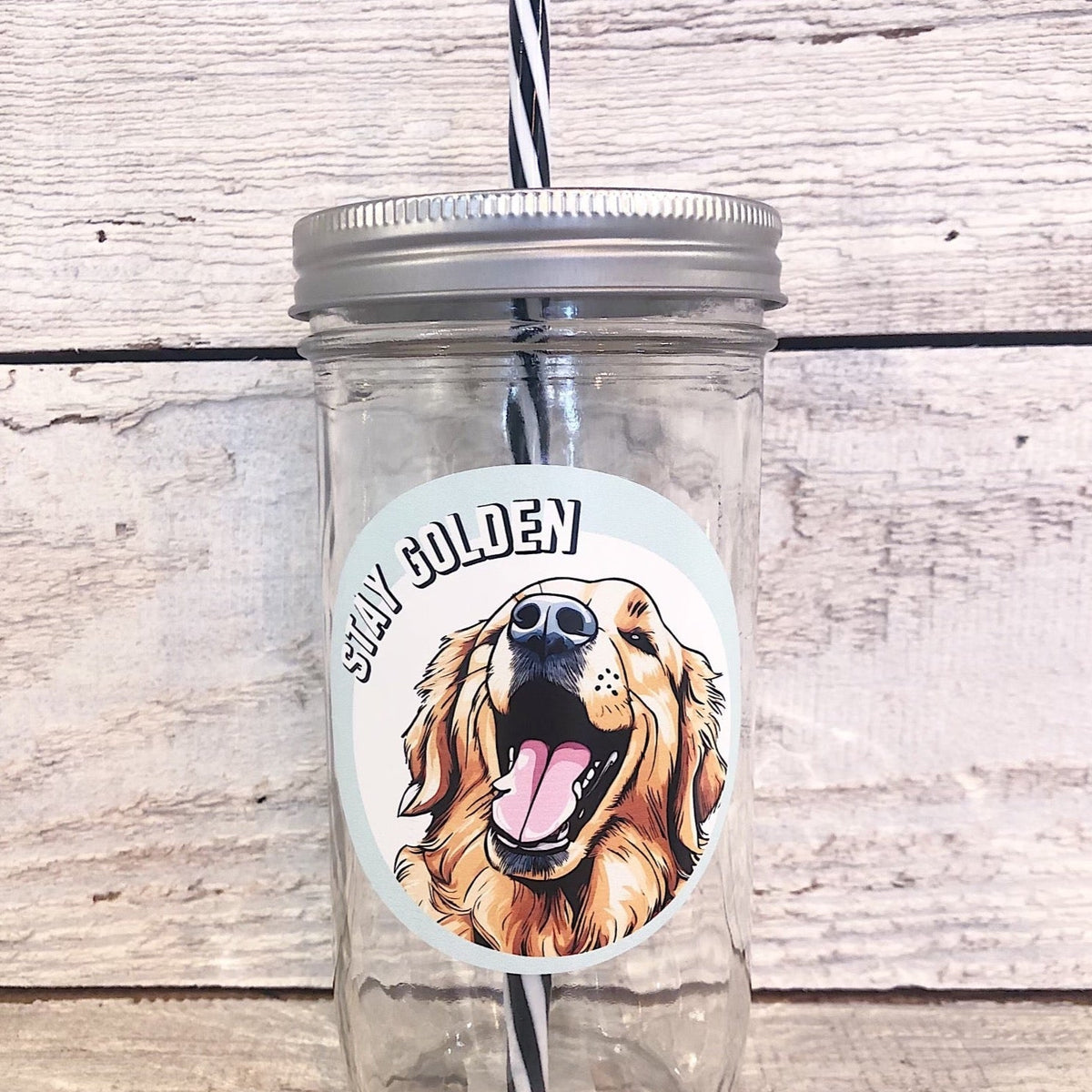 Mason jar tumbler that has a circular decal with a golden retriever face and reads “stay golden”