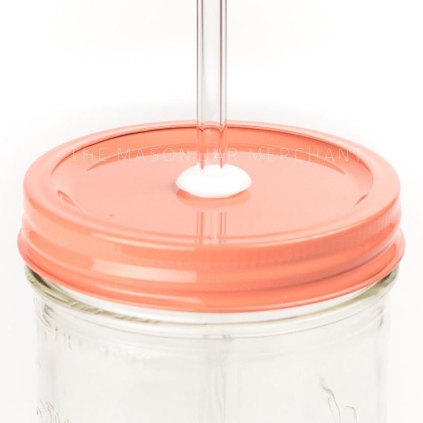 Close-up of a 24 oz mason jar with a coral coloured painted straw lid and a glass straw