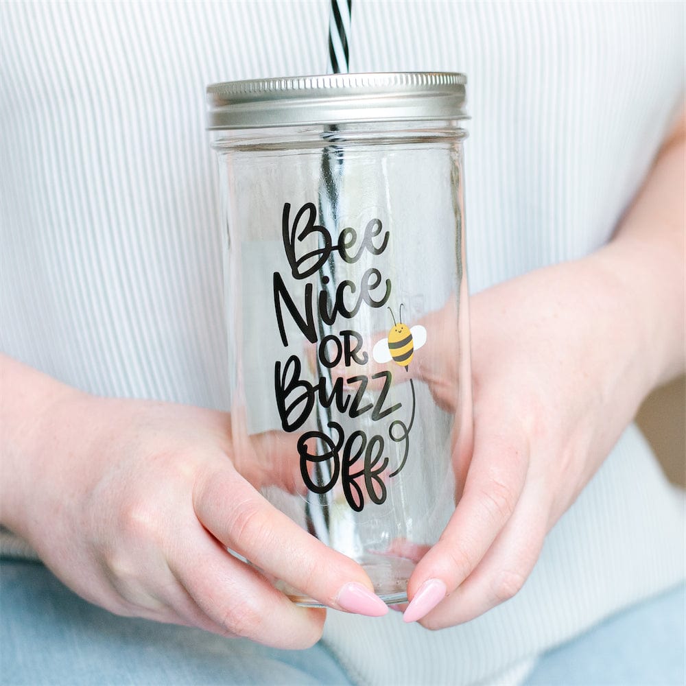 A close up of Photo of a mason jar tumbler with a print that says "bee nice or buzz off".
