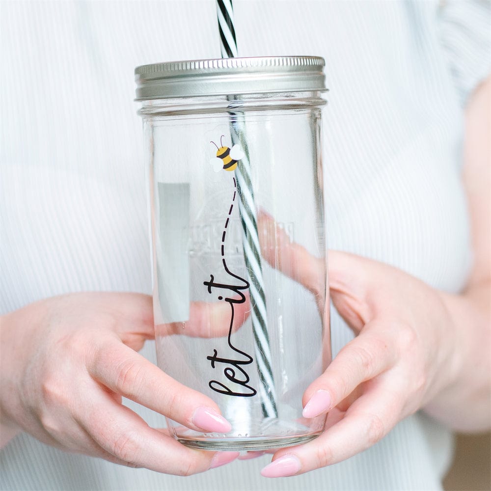 A close up of a Photo of a mason jar tumbler with a text that says "Let it Bee (Bee in a drawing).
