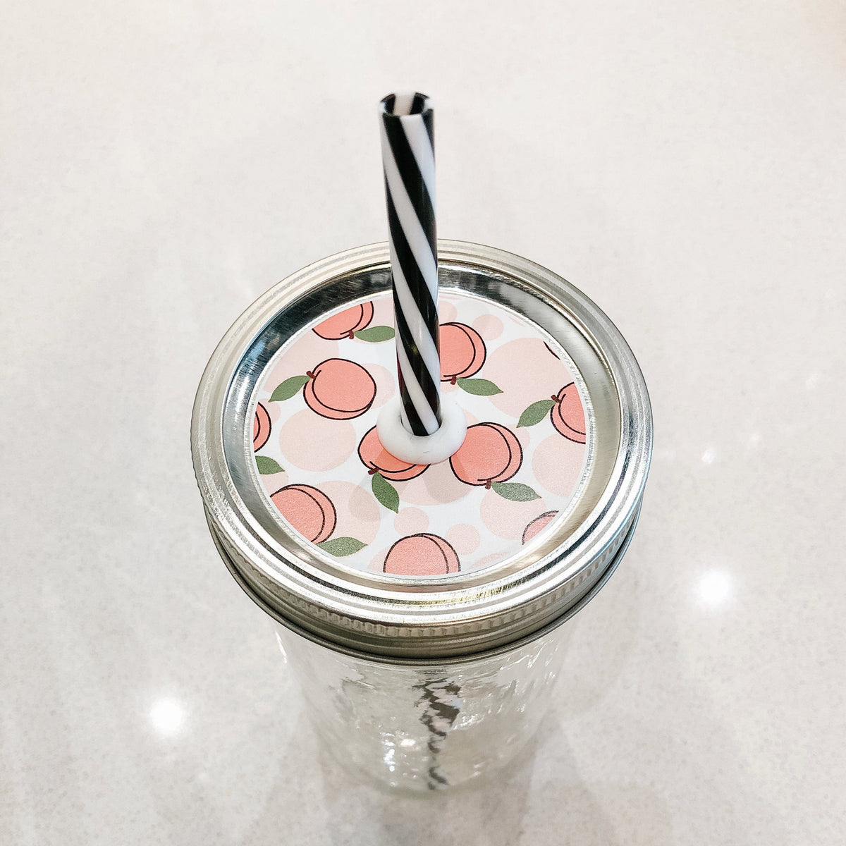 Photo of a peach mason jar straw lid with a black and white straw