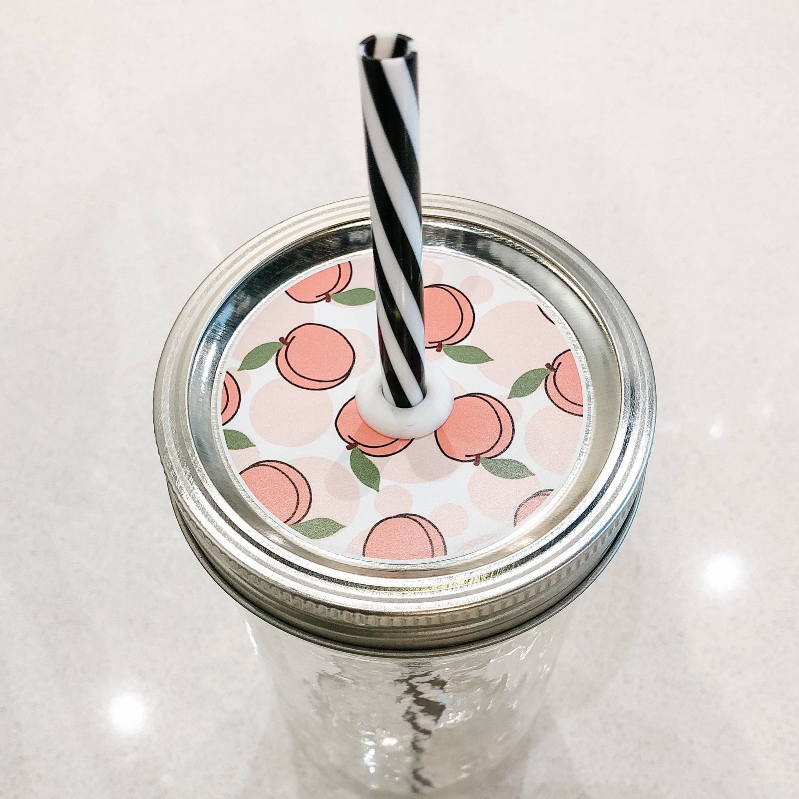 Photo of a peach mason jar straw lid with a black and white straw