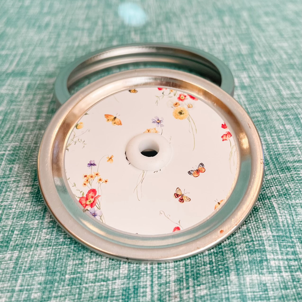 straw lid with a white background, bundles of flowers and butterflies scattered throughout
