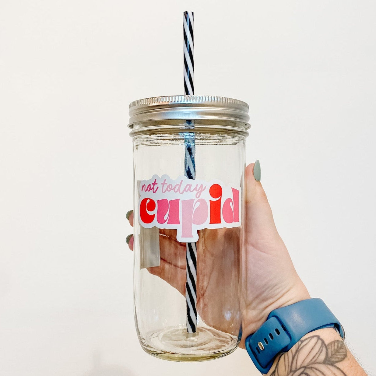 hand holding a mason jar tumbler that says "not today cupid" in different shades of pink and red