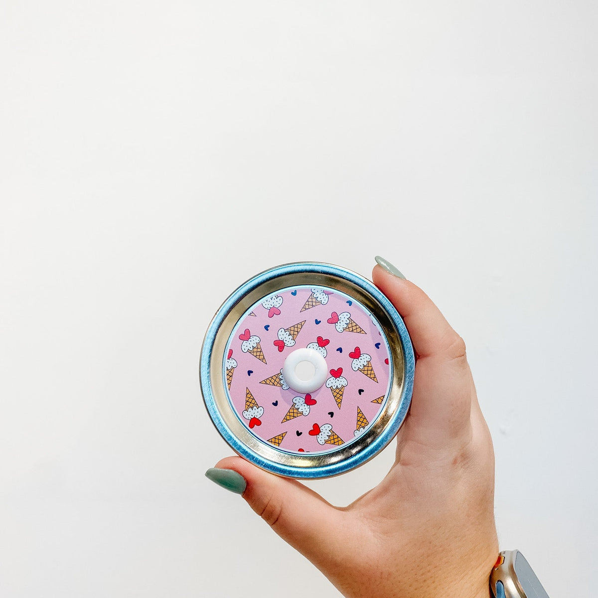 straw lid with a pink background and small ice cream cones scattered across, as well as small black hearts. The ice cream cones have a red heart in place of a cherry