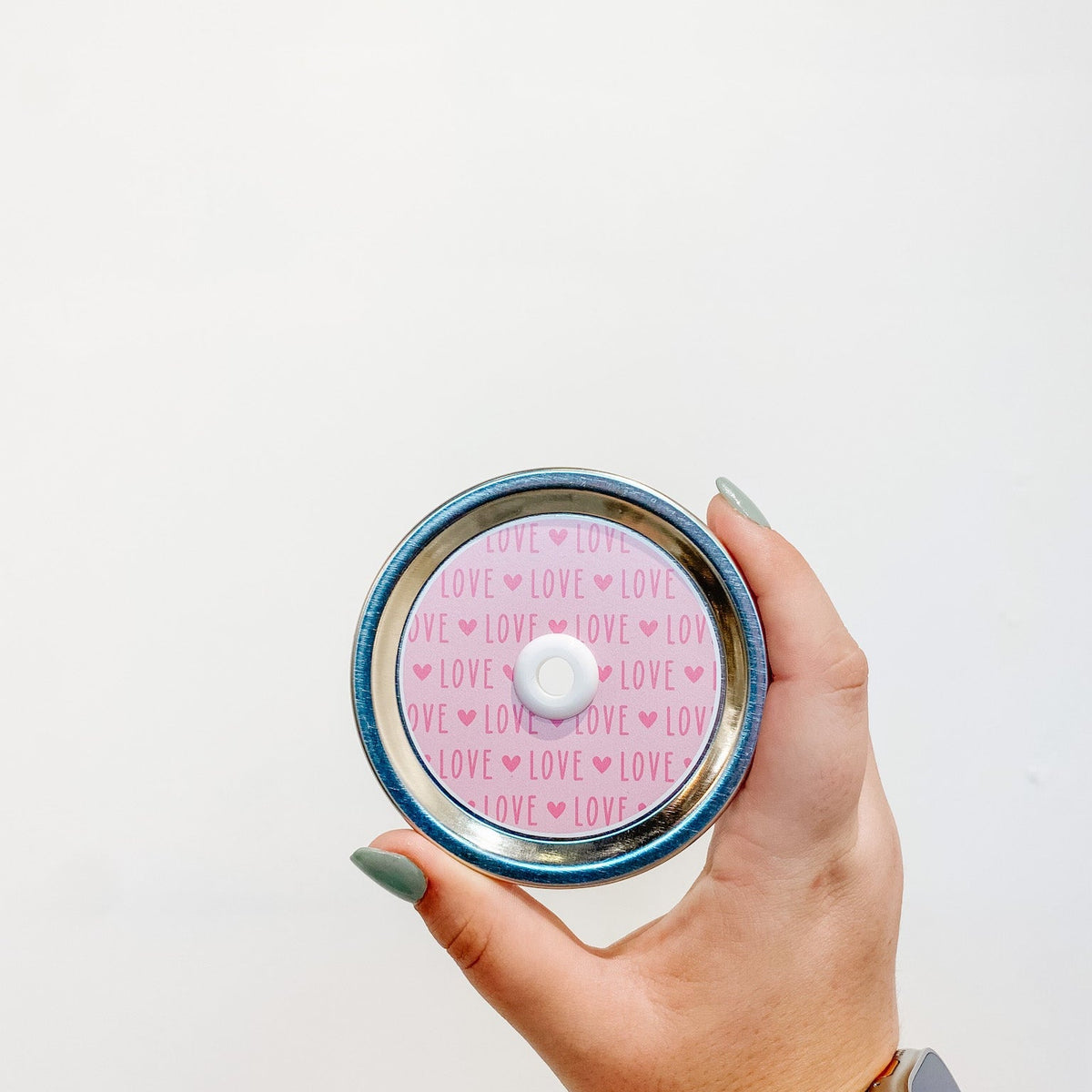 straw lid that has the word "LOVE" repeated with a small heart in between each word. The word and heart are in a deeper pink colour with a light pink background