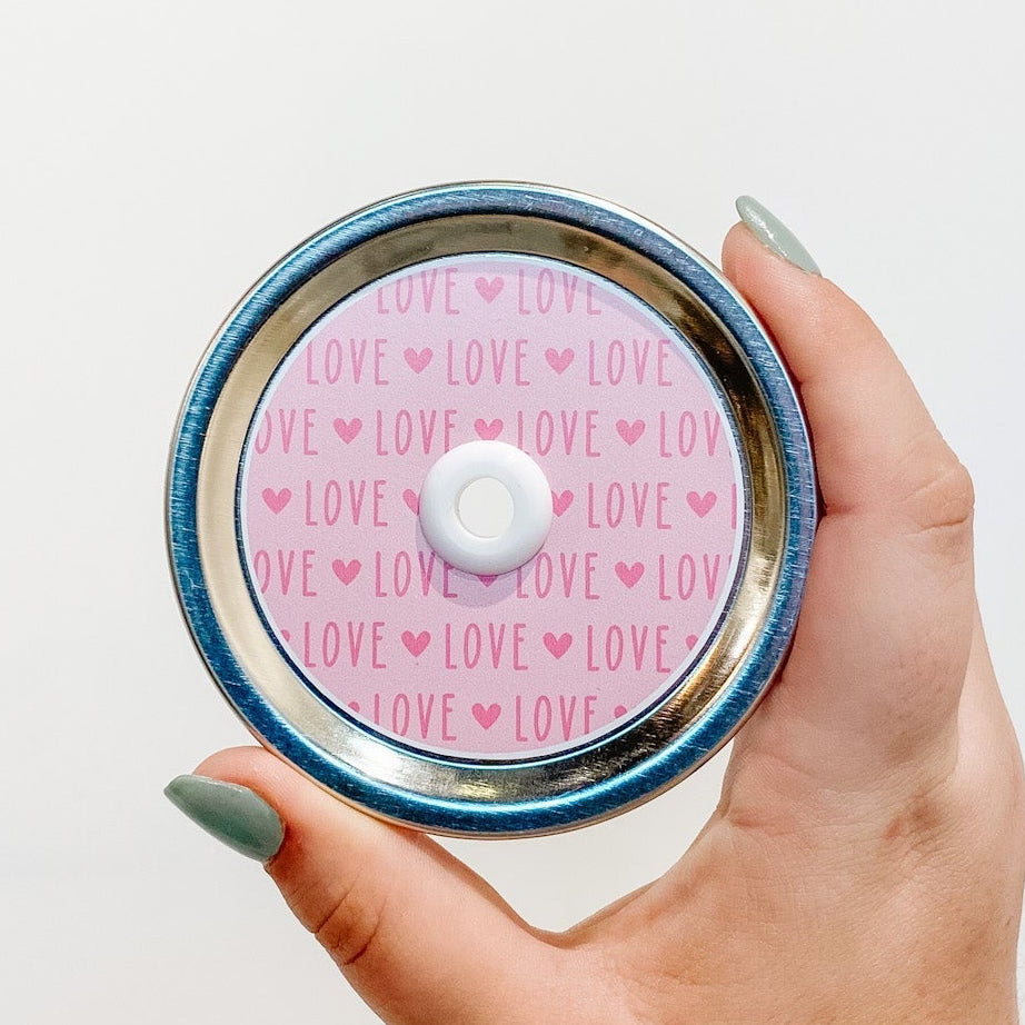 straw lid that has the word "LOVE" repeated with a small heart in between each word. The word and heart are in a deeper pink colour with a light pink background