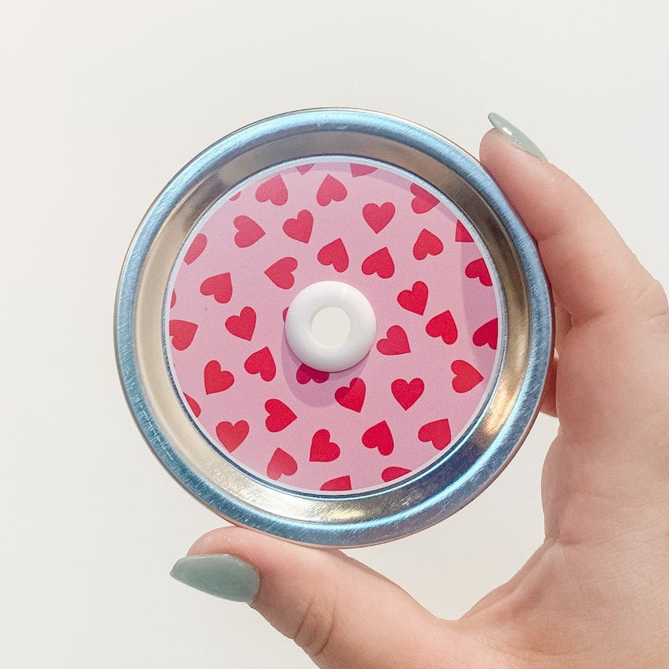 straw lid that has a pink background with red hearts scattered across