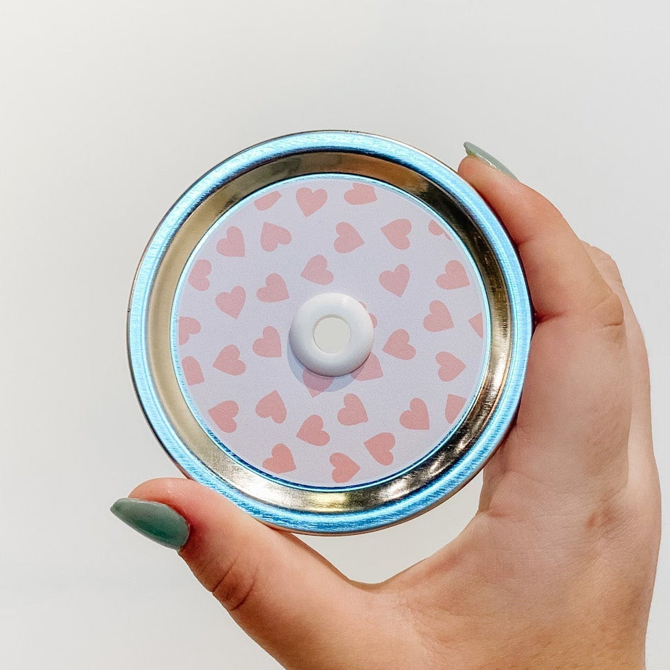 straw lid with a pale pink background and deeper pink hearts scattered across