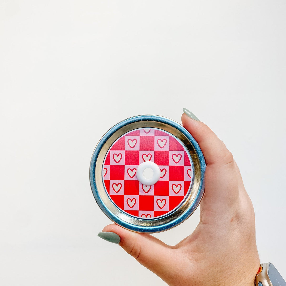 straw lid that has a pink and red checkerboard pattern, the pink squares also have a cream coloured heart in each