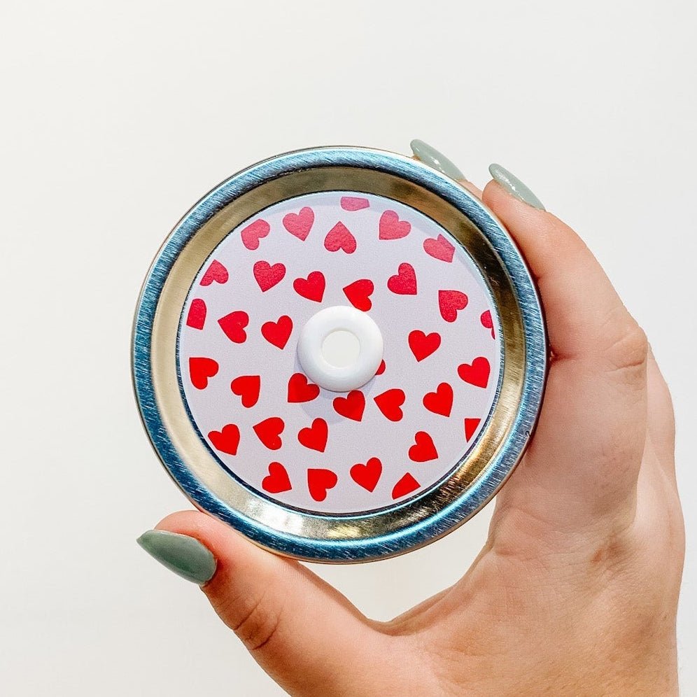 straw lid with a pale pink background and red hearts scattered across