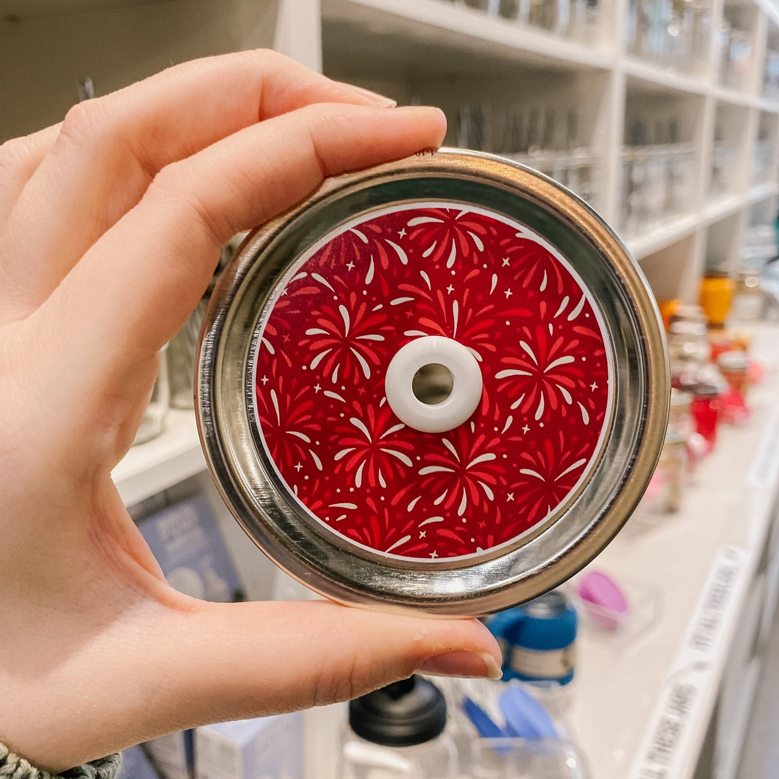 a straw lid with a dark red background with red and white fireworks across the lid