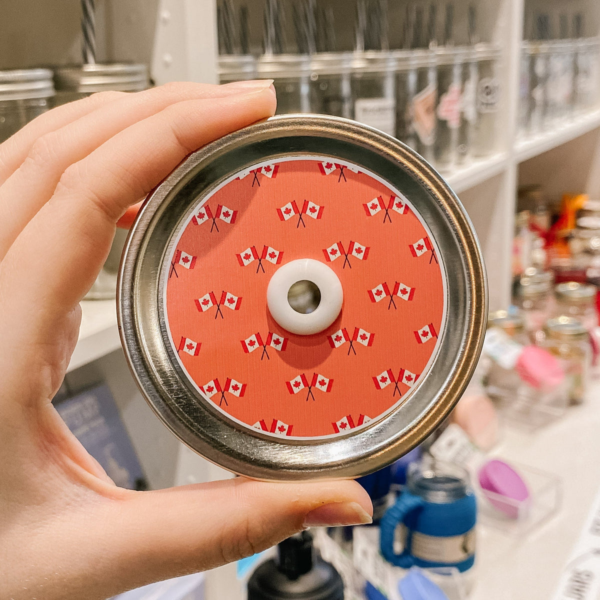 straw lid with a light red background, with two Canadian flags criss crossing multiple times patterned across the lid