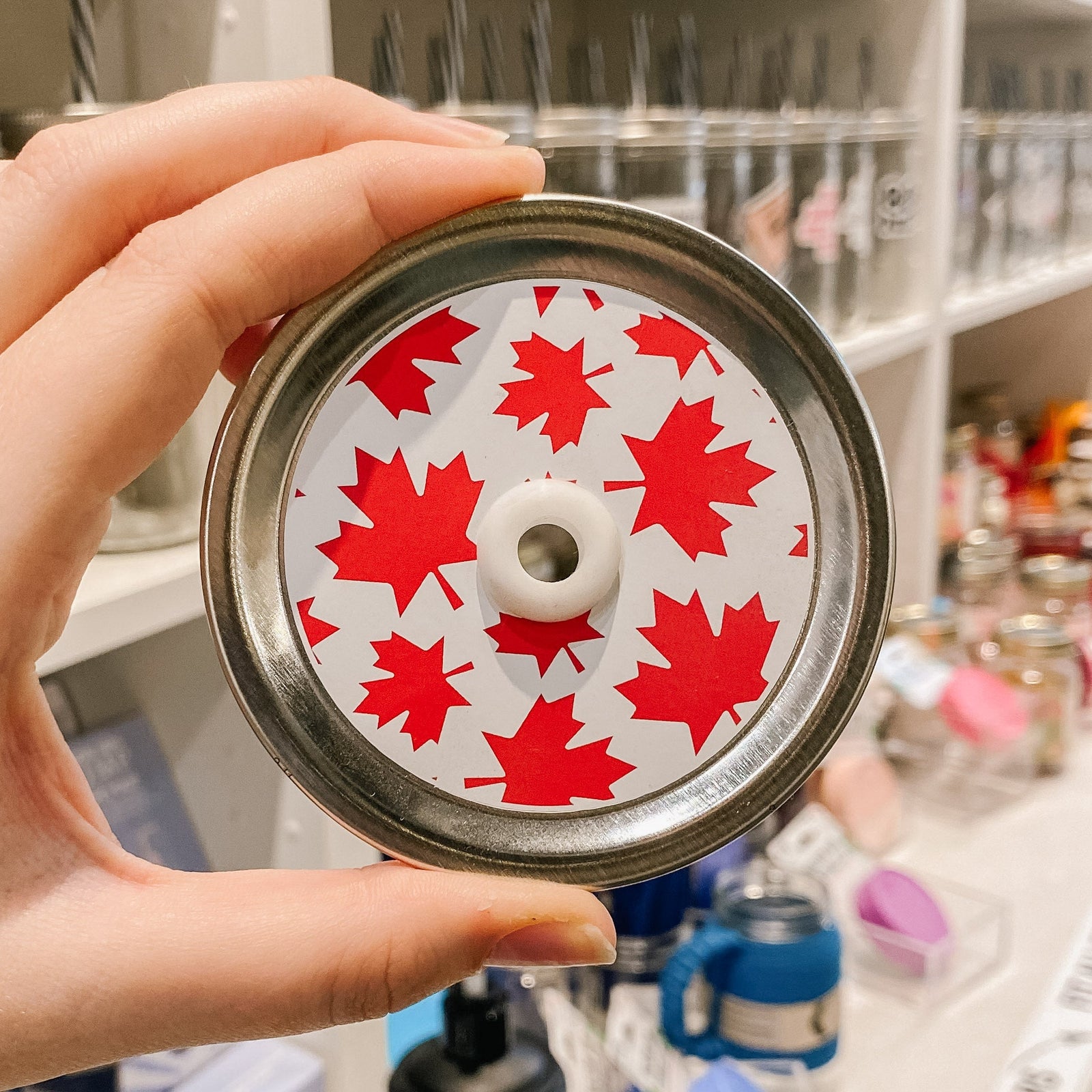 straw lid with a white background with red maple leaves of various sizes across the lid