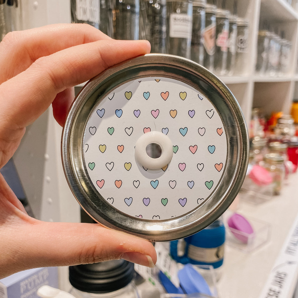 straw lid with a white background with multicolour hearts patterned across the lid