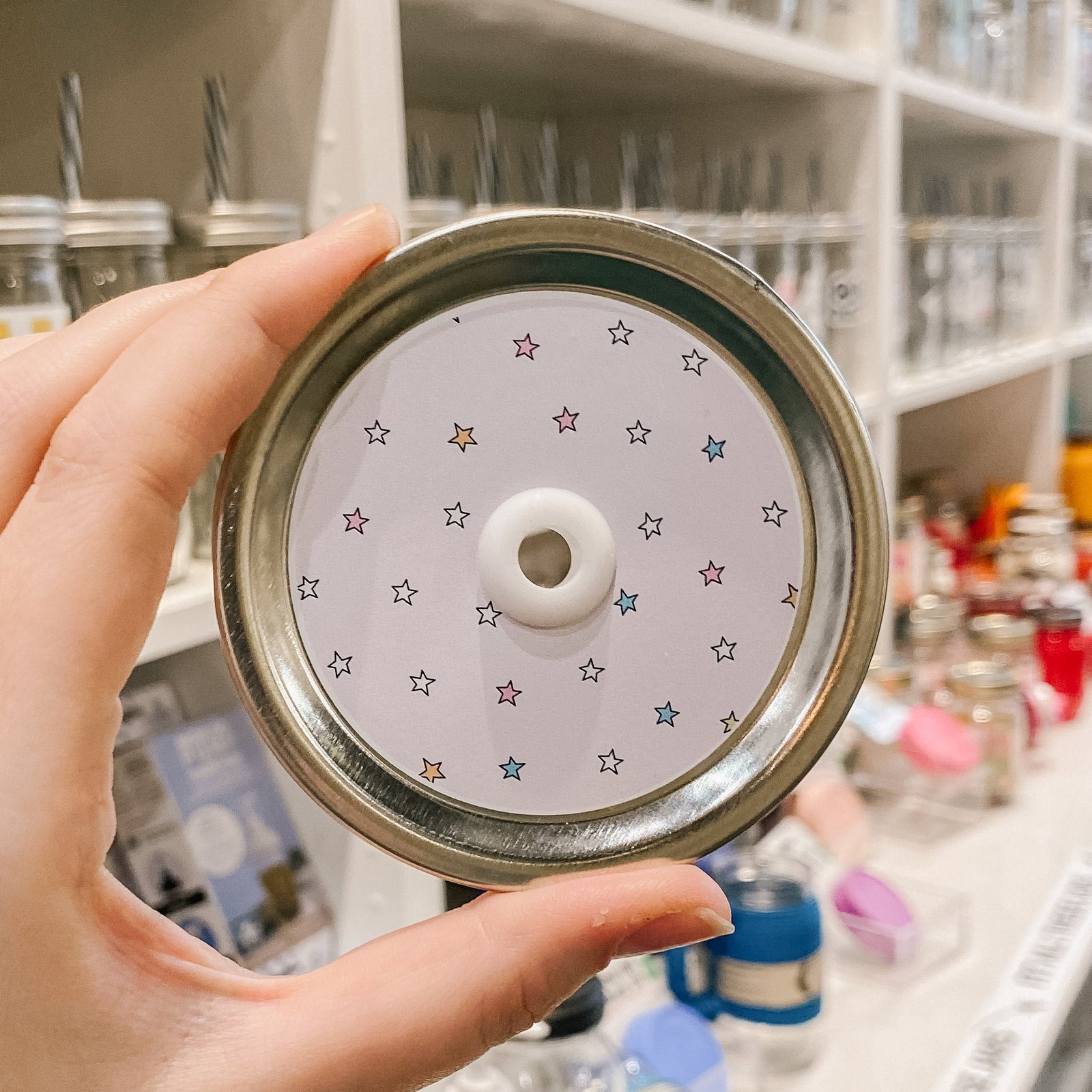 a straw lid that has a white background with multicoloured stars spread across