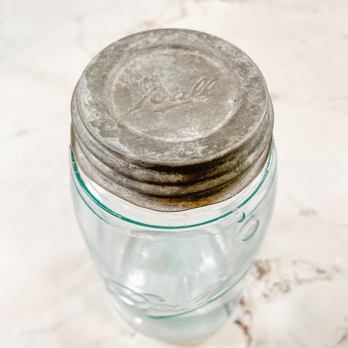 close up of a vintage zinc lid from Ball. it is on top of a mason jar