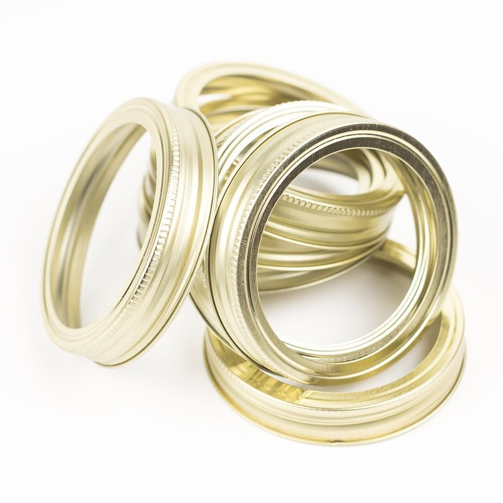 close up of a gold wide mouth canning lid and ring on a white background