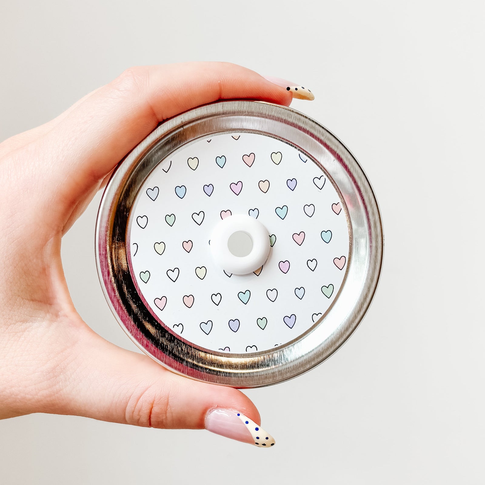 straw lid with a white background with multicolour hearts patterned across the lid