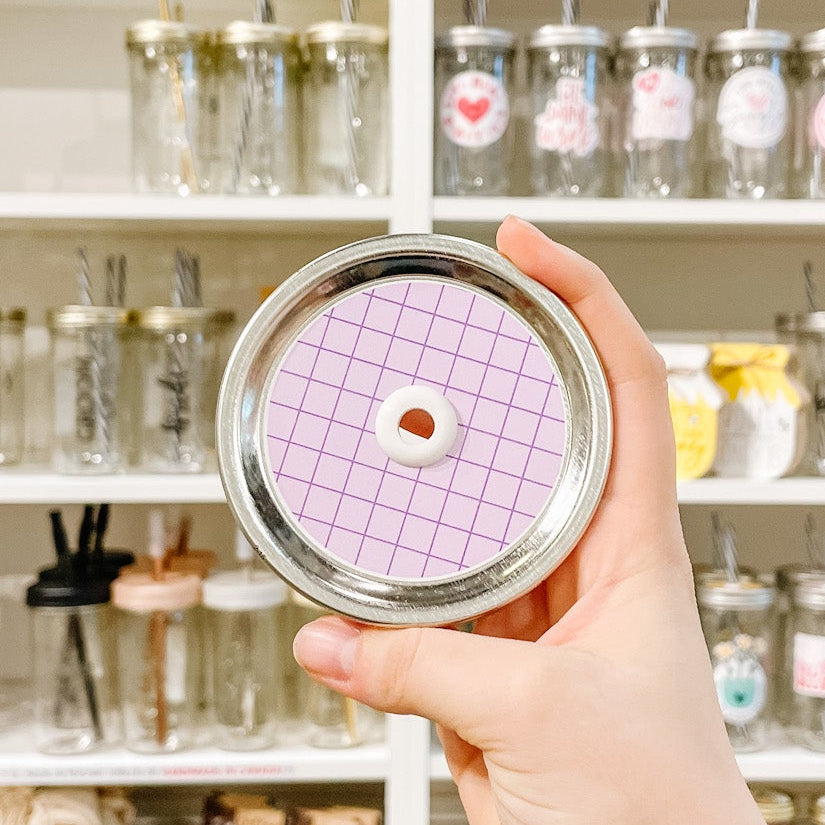 Hand holding a mason jar patterned straw lid With a purple grid design