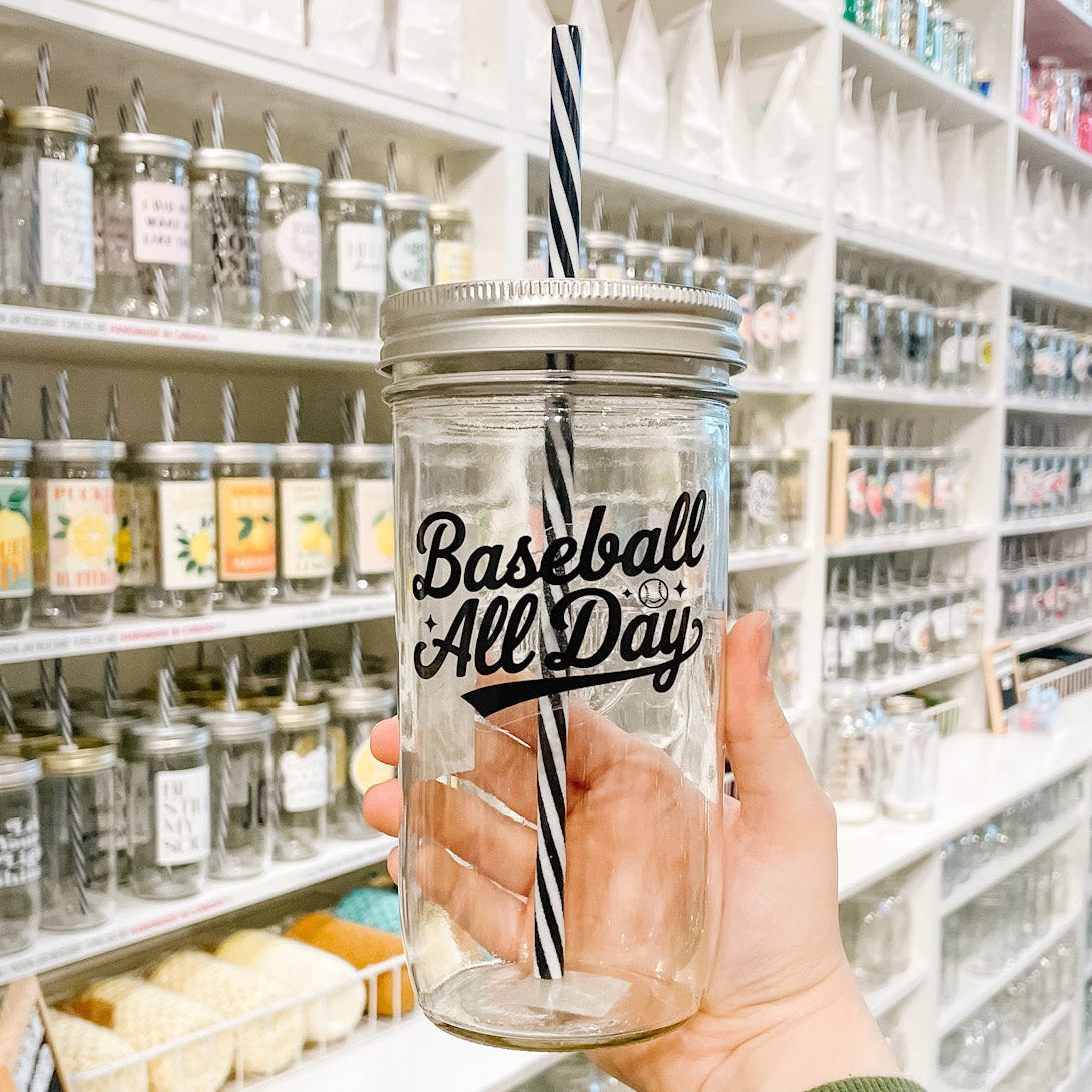 Hand holding a mason jar tumbler that reads baseball all day in black text on clear background