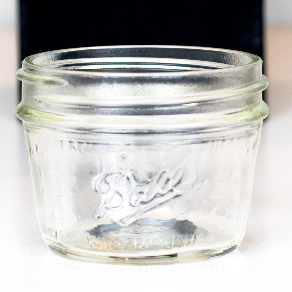 A ball wide mouth half pint mason jar against a white background with a hand holding it for size reference