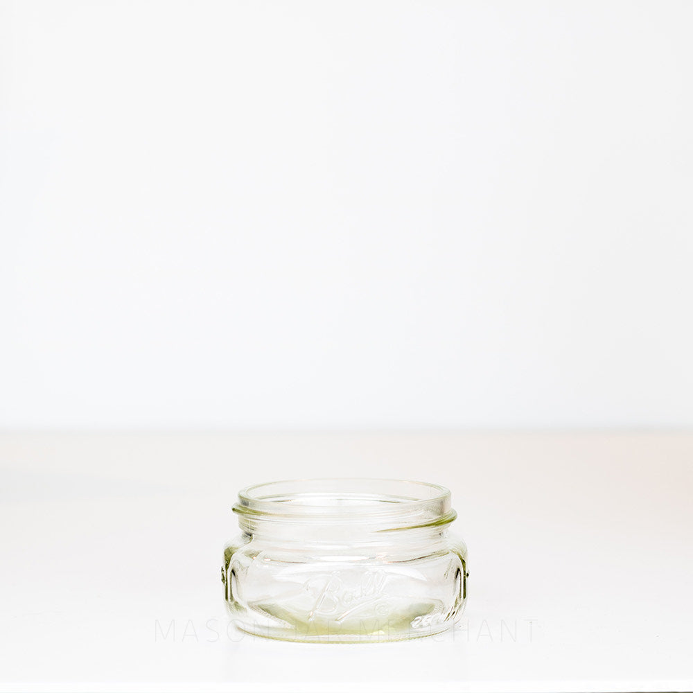 Unique shallow wide mouth half pint mason jar with Ball logo against a white background
