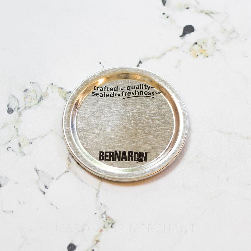 Close up of Bernardin silver canning lid against a marble countertop