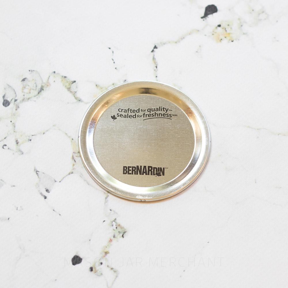 close up of a regular mouth Bernardin canning lid on a marble white background