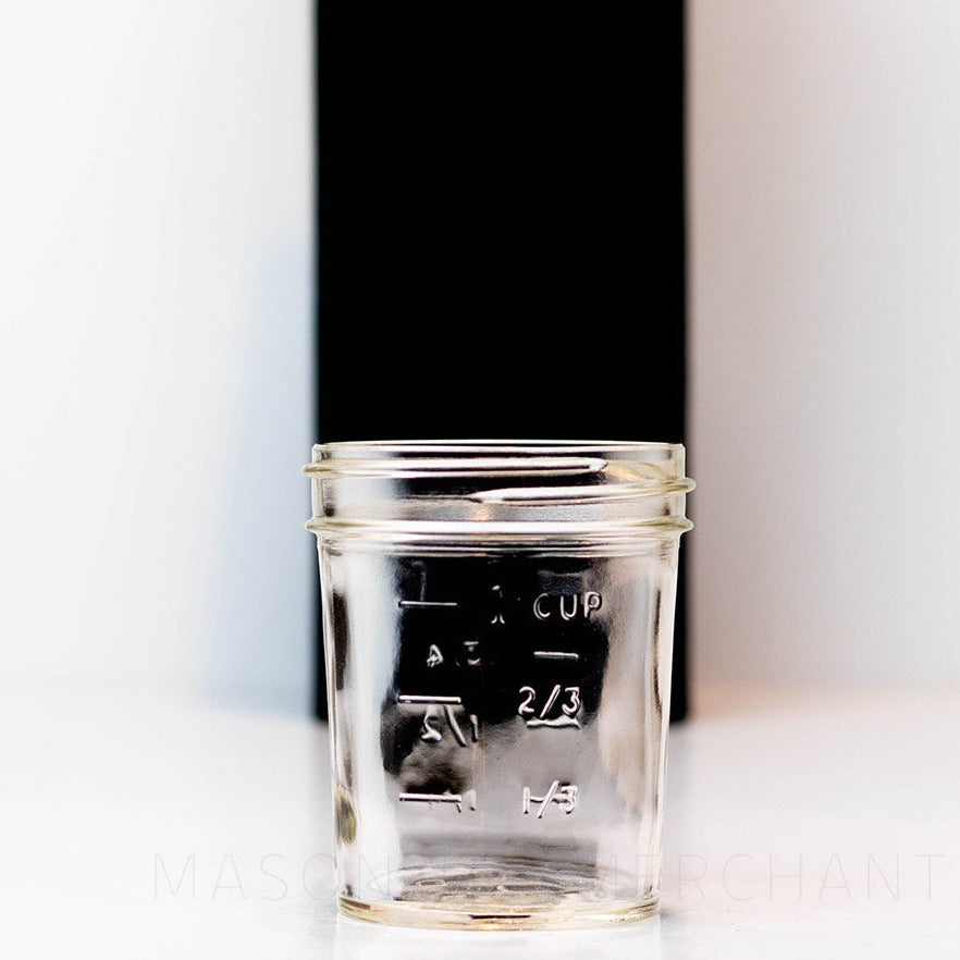 Back of a Regular mouth half pint mason jar with straight sides against a white background. It has a measurements engraved.