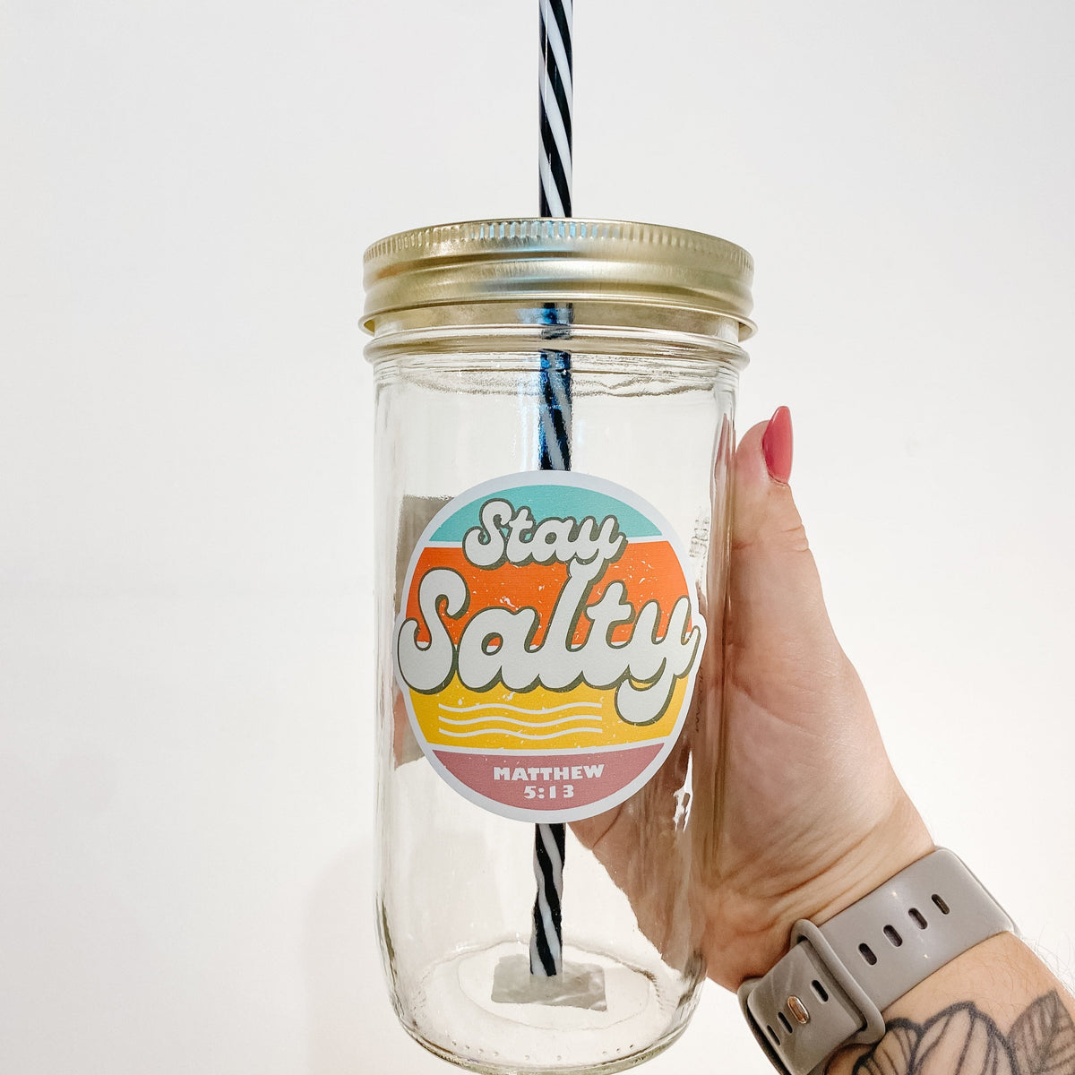 Hand holding a mason jar tumbler that says "stay salty" in big letters and "Matthew 5:13" lower in smaller text.
