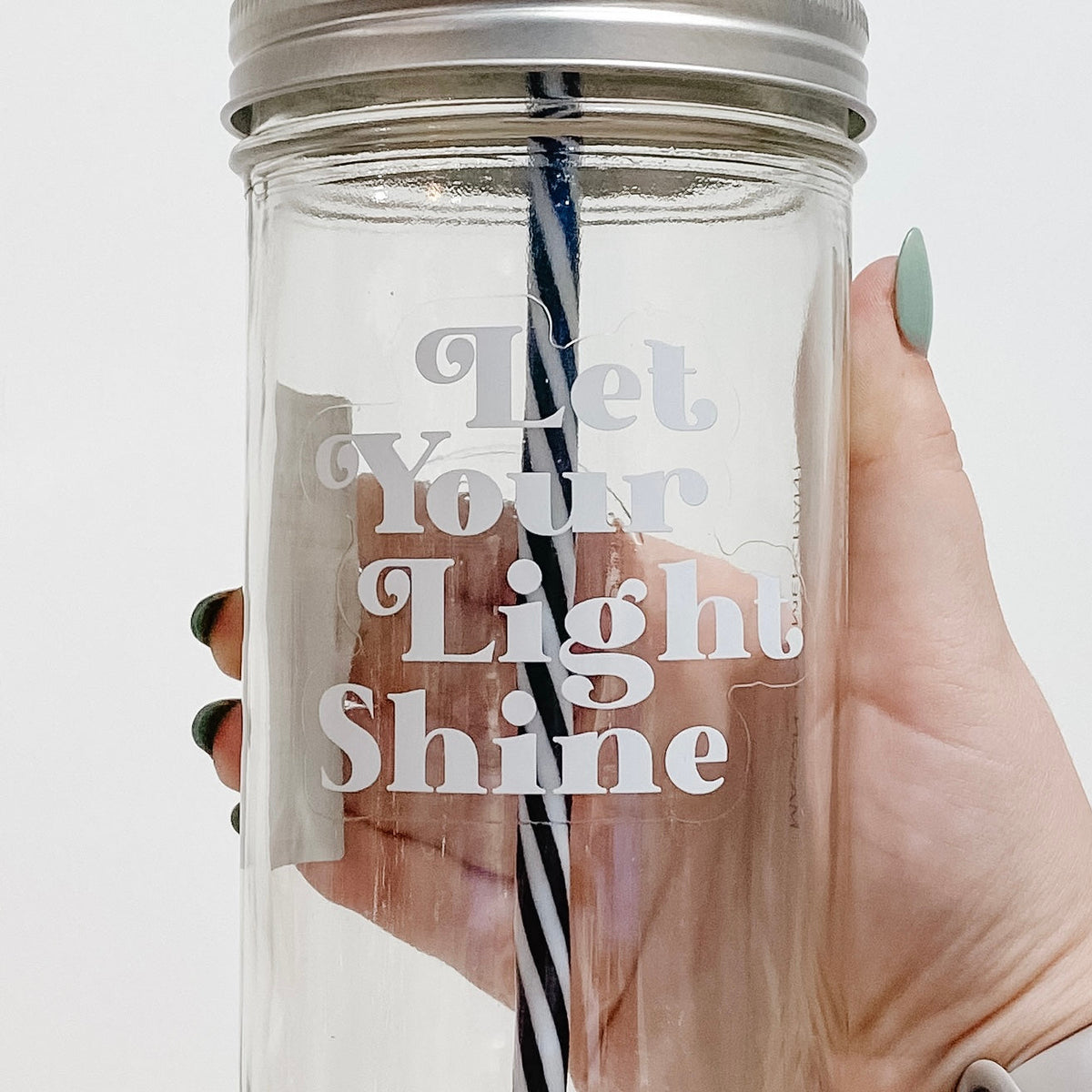 Close up of a mason jar tumbler that says “let your light shine” in white letters