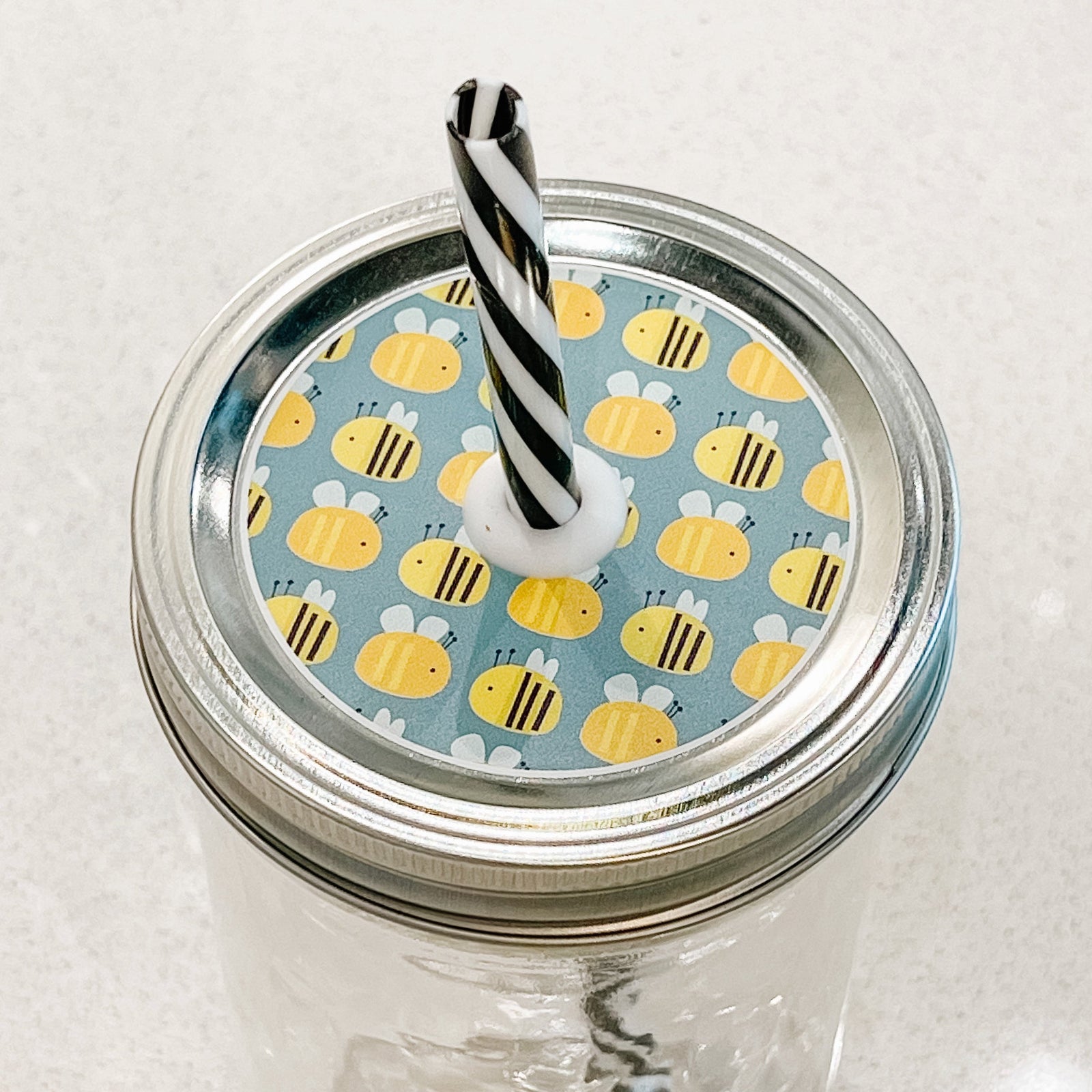 top photo of mason jar lid with bees and a light blue background