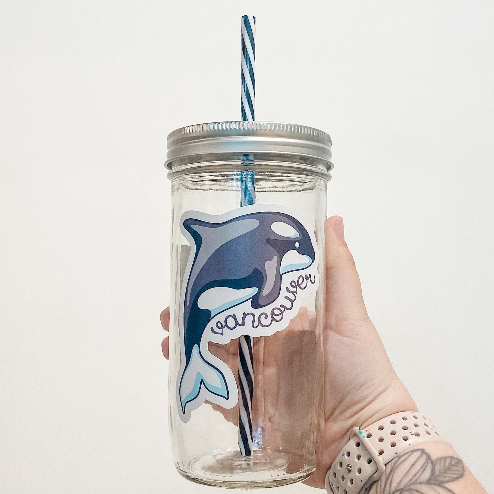 Hand holding mason jar that reads Vancouver with orca.