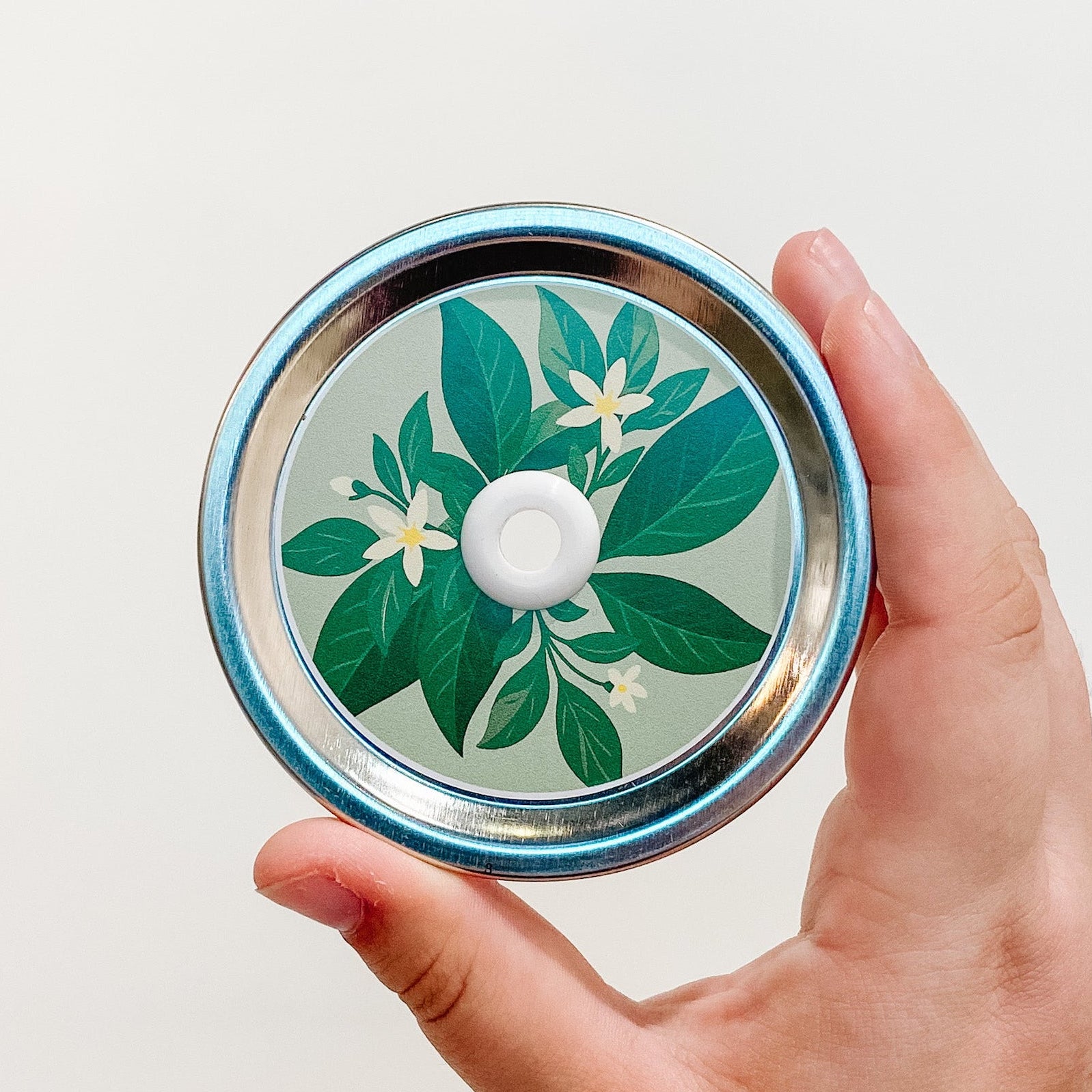 Hand holding a key lime tart patterned mason jar straw lid with green citrus design