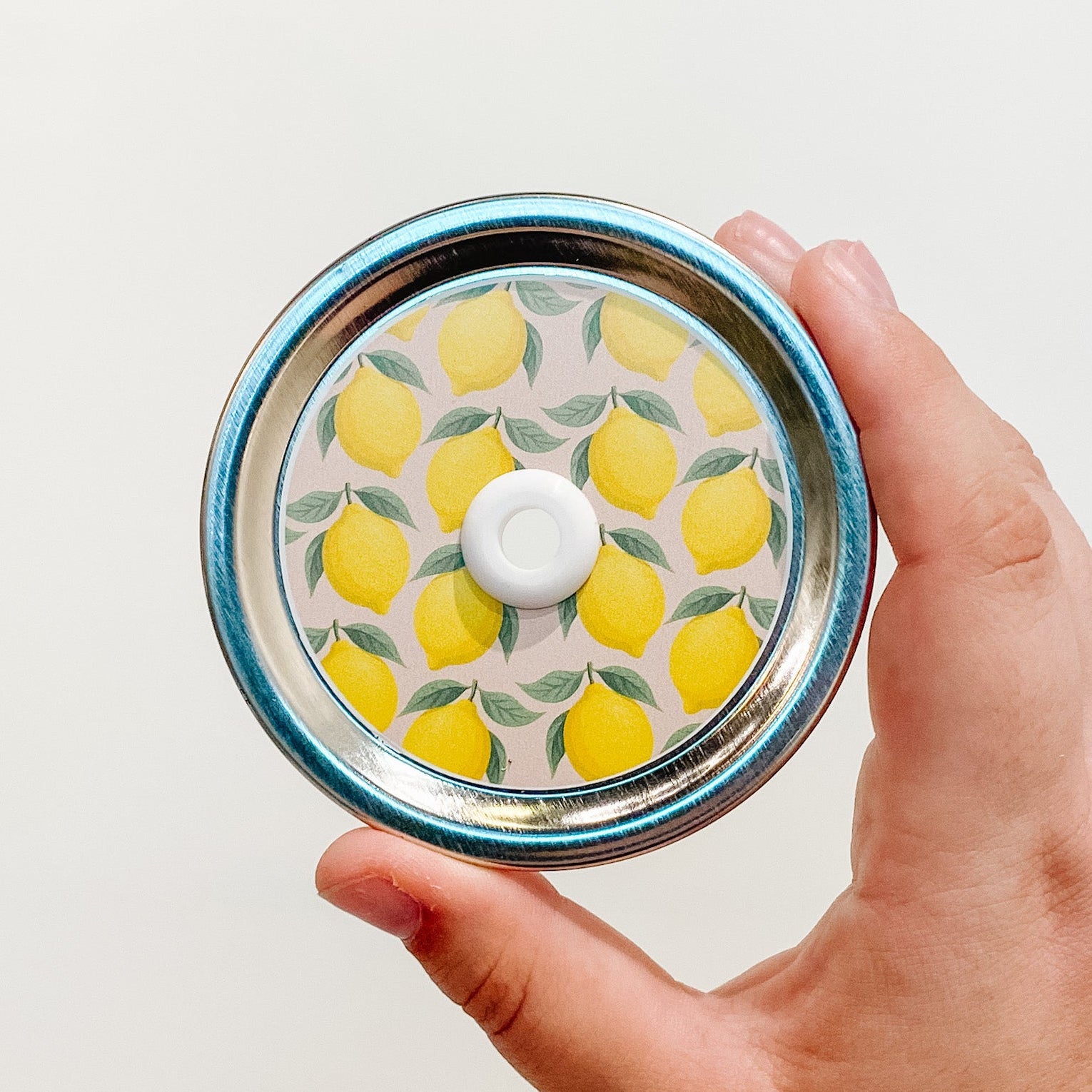 Hand holding a sour-then-sweet lemon patterned mason jar straw lid with gradient citrus design
