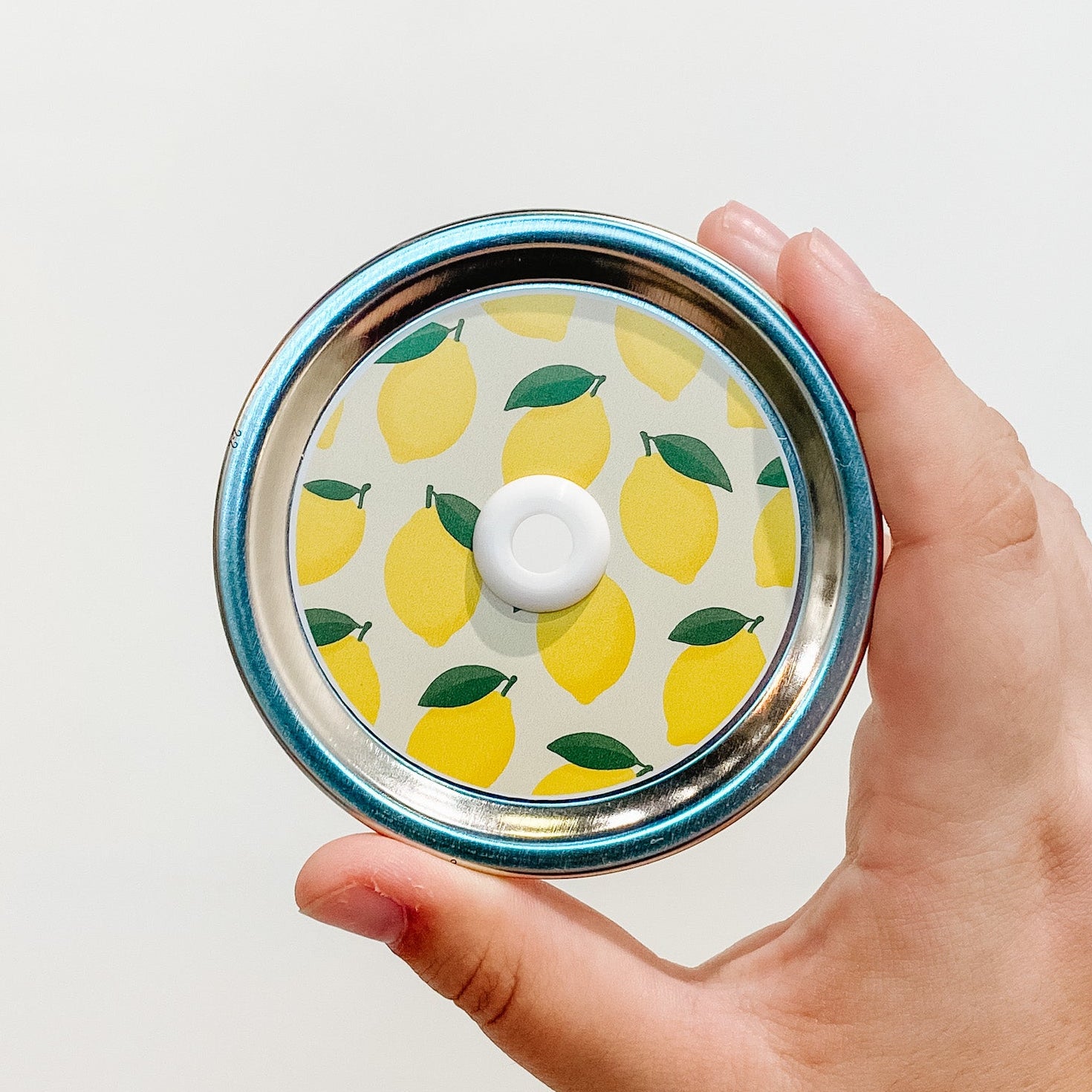 Hand holding a watermelon rind patterned mason jar straw lid with green stripe design
