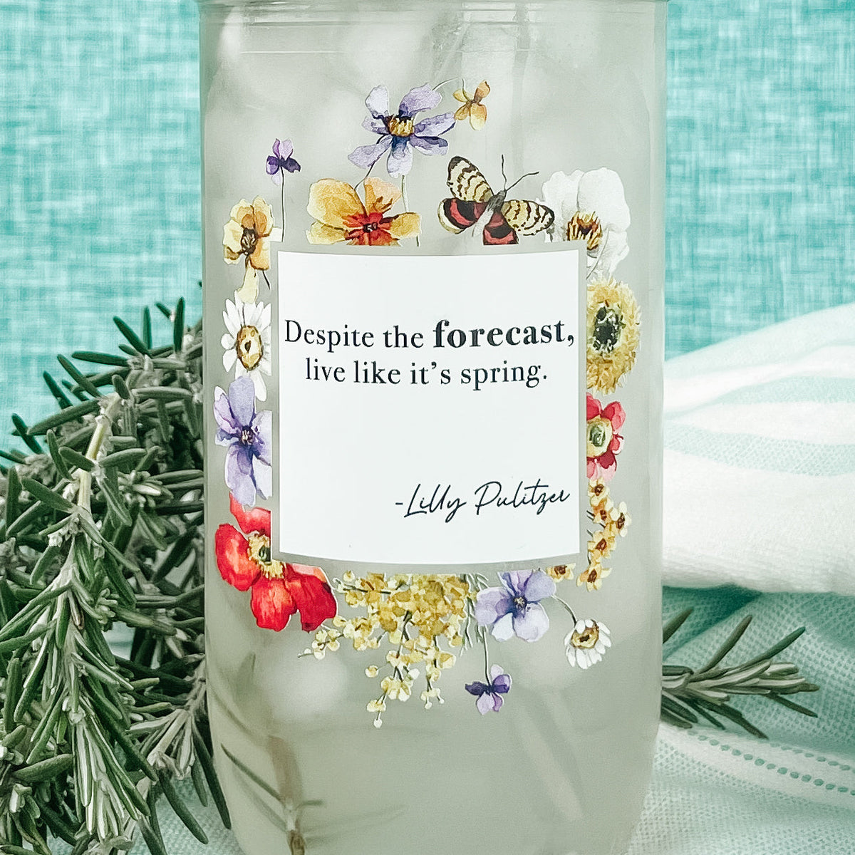 Close up of a mason jar tumbler that says “Despite the forecast, live like it’s spring. -Lilly Pulitzer” with flowers and butterflies creating a box around the words.