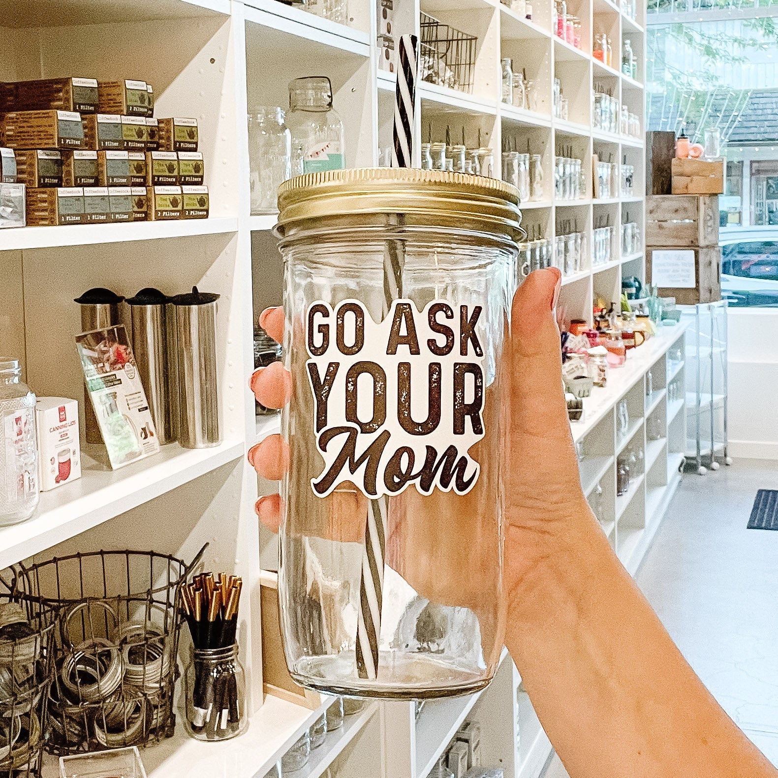 Hand holding a mason jar tumbler that says “go ask your mom”