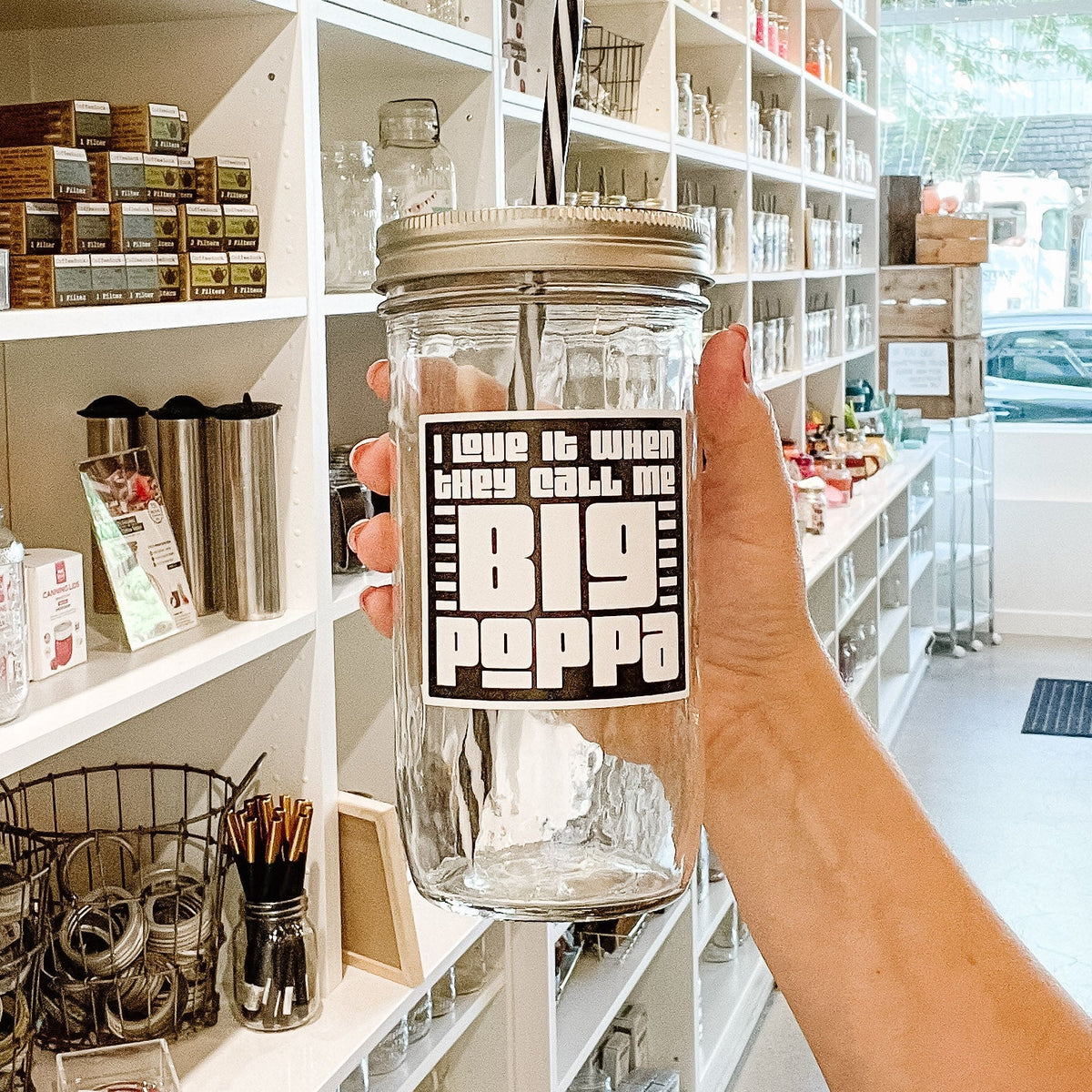 Close up of a mason jar tumbler that has a black square decal that reads “I love it when they call me big poppa” in white block letters