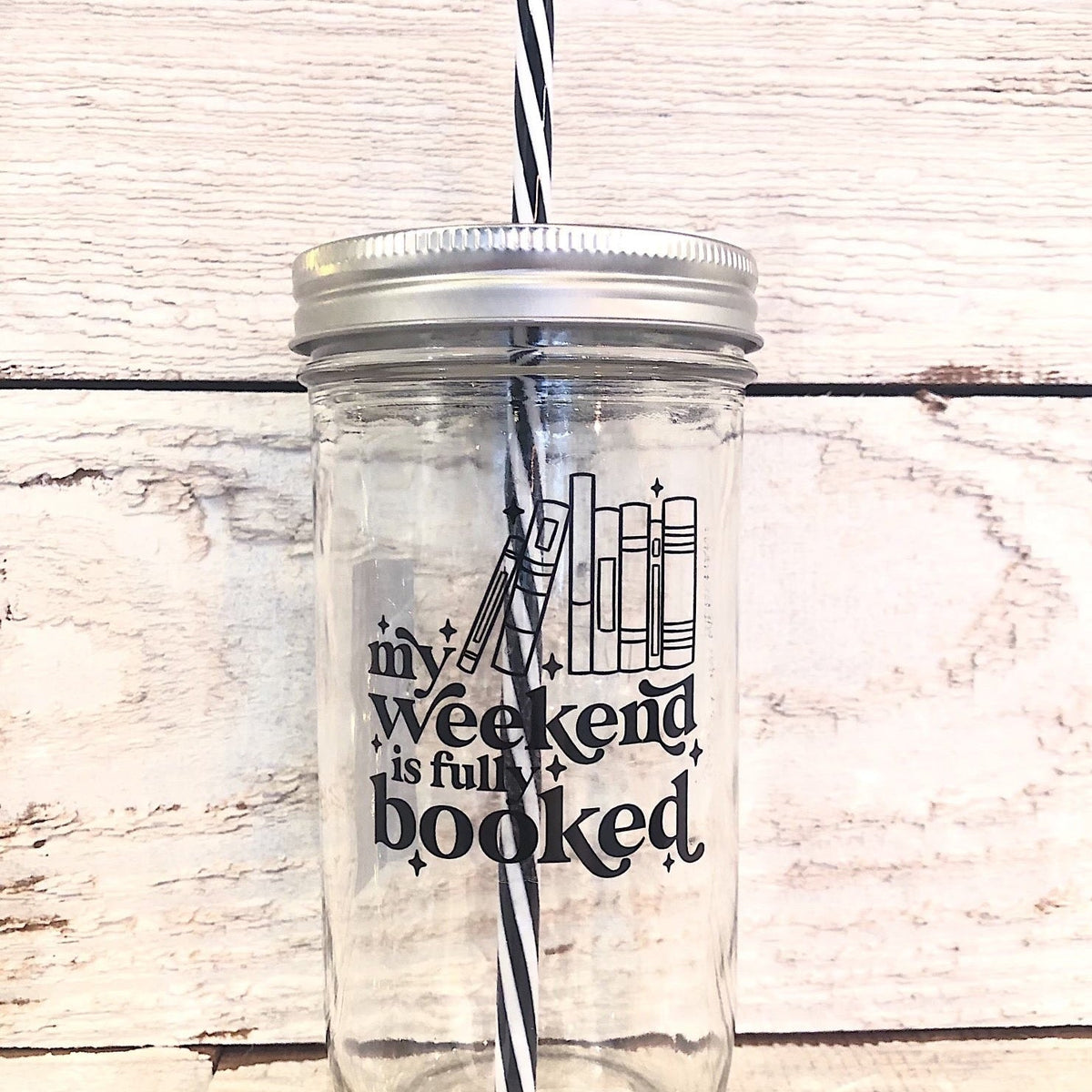 Mason jar tumbler that says “my weekend is fully booked” with black outlines of books