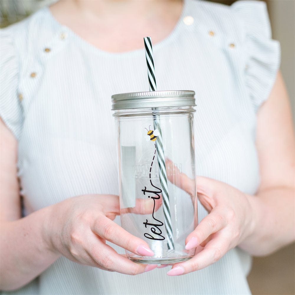 Photo of a mason jar tumbler with a text that says "Let it Bee (Bee in a drawing).