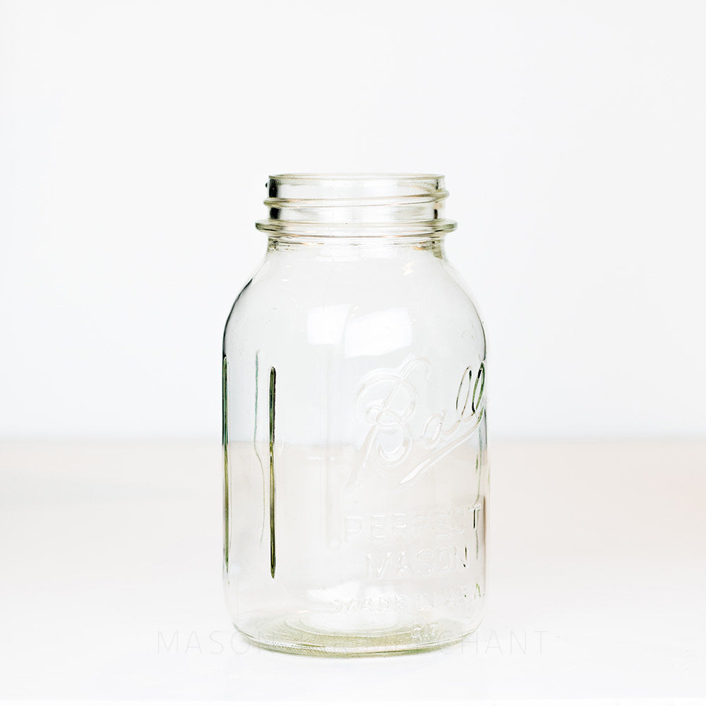 side view of a Ball regular mouth quart mason jar with logo showing on a white background